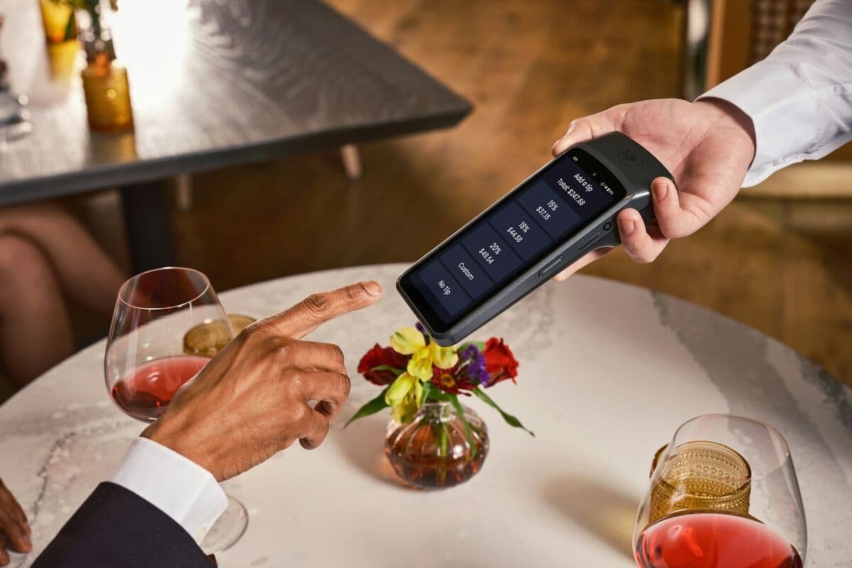 A diner pays the bill on a card terminal at a restaurant table