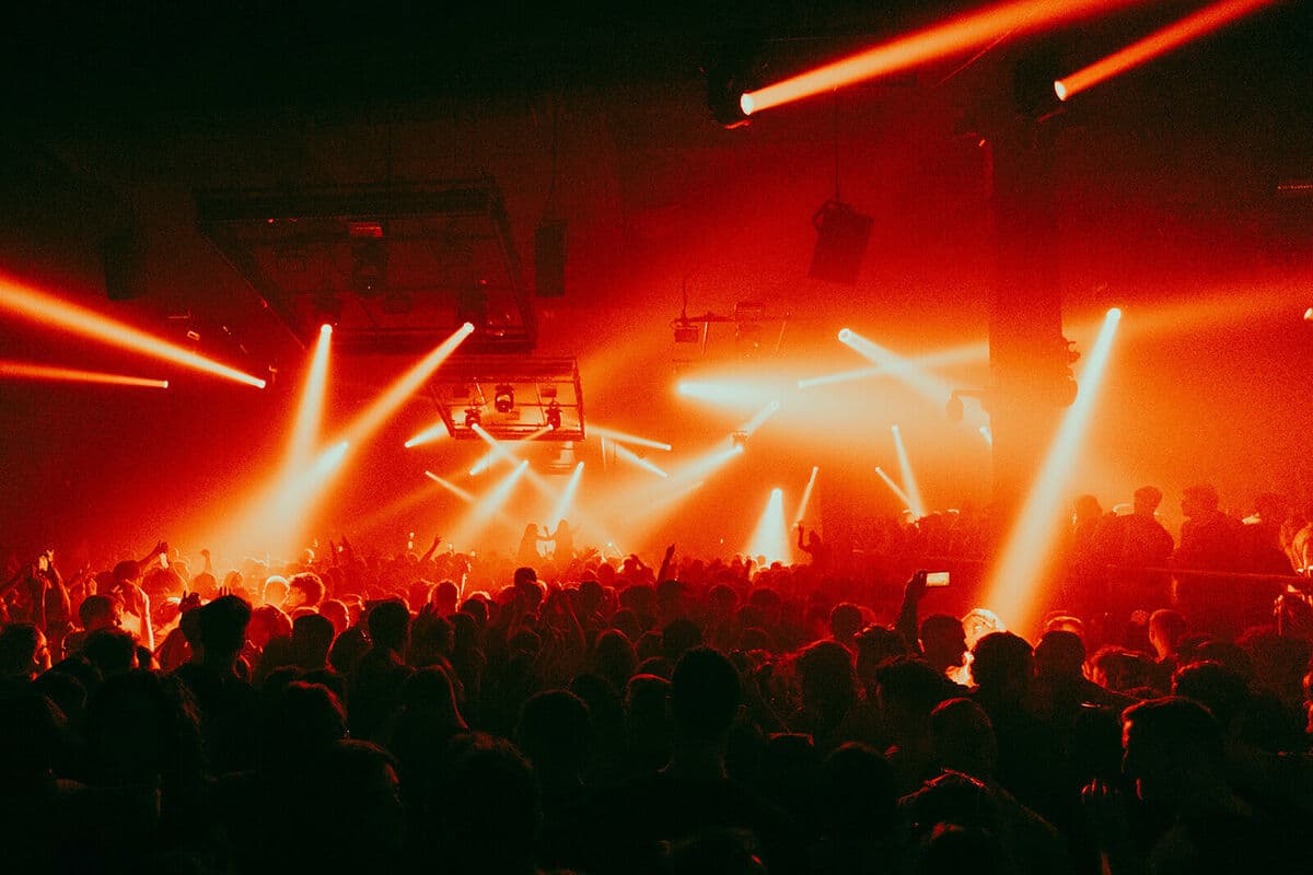 Red stage lights over a packed crowd at The Warehouse Project