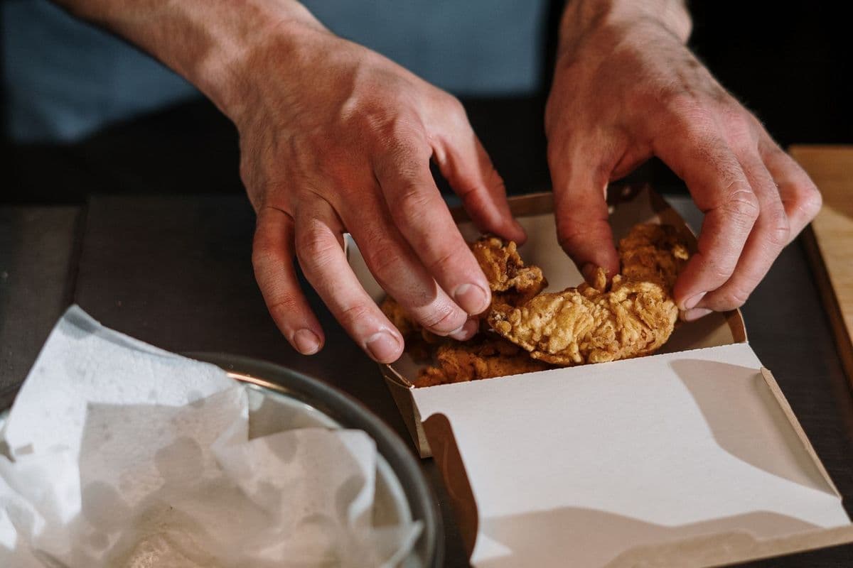 A cook holding a tray of fried food in a kitchen