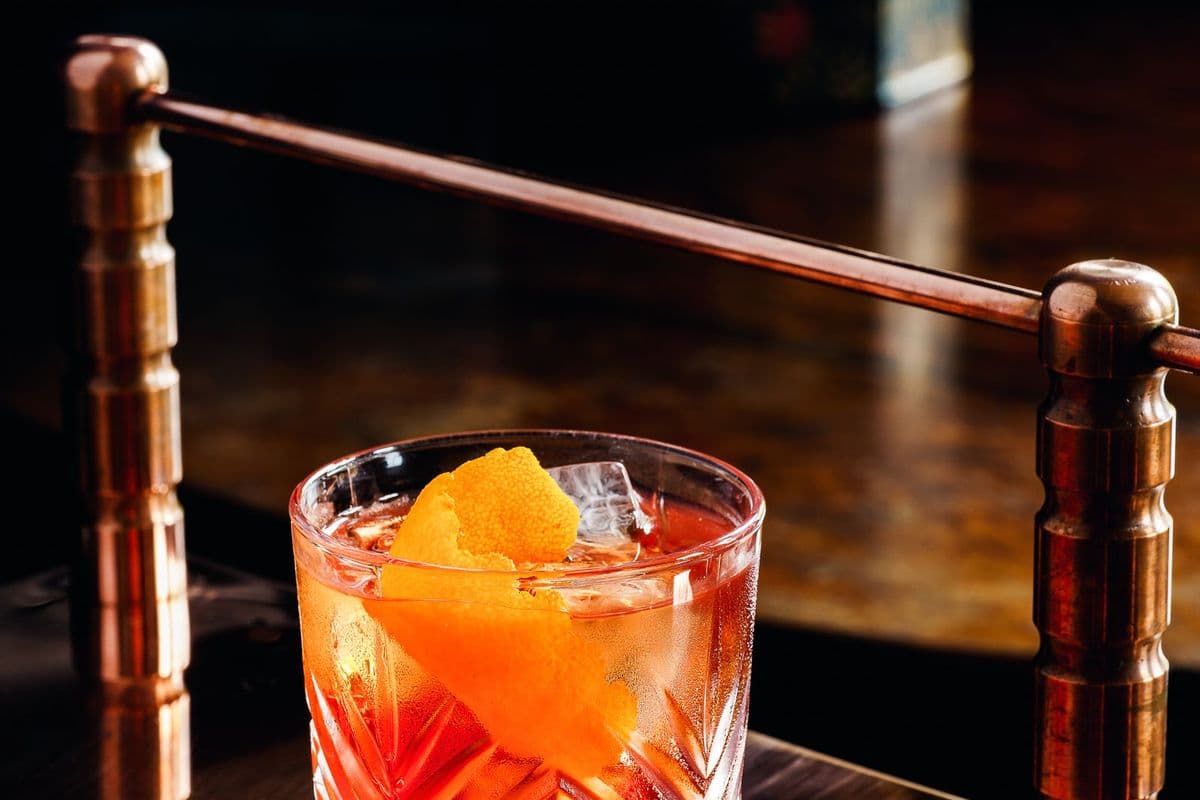 A negroni with ice and an orange twist on a bar