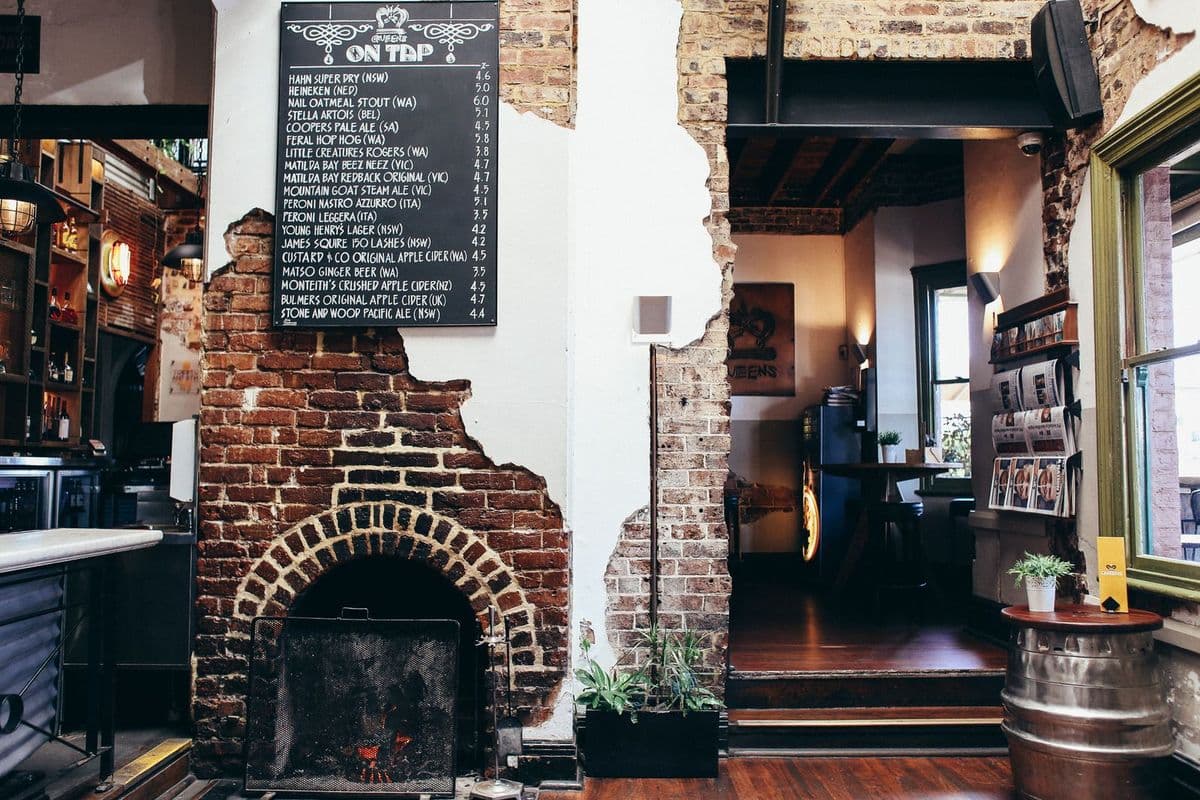 A brick fireplace and a chalkboard menu inside a traditional pub