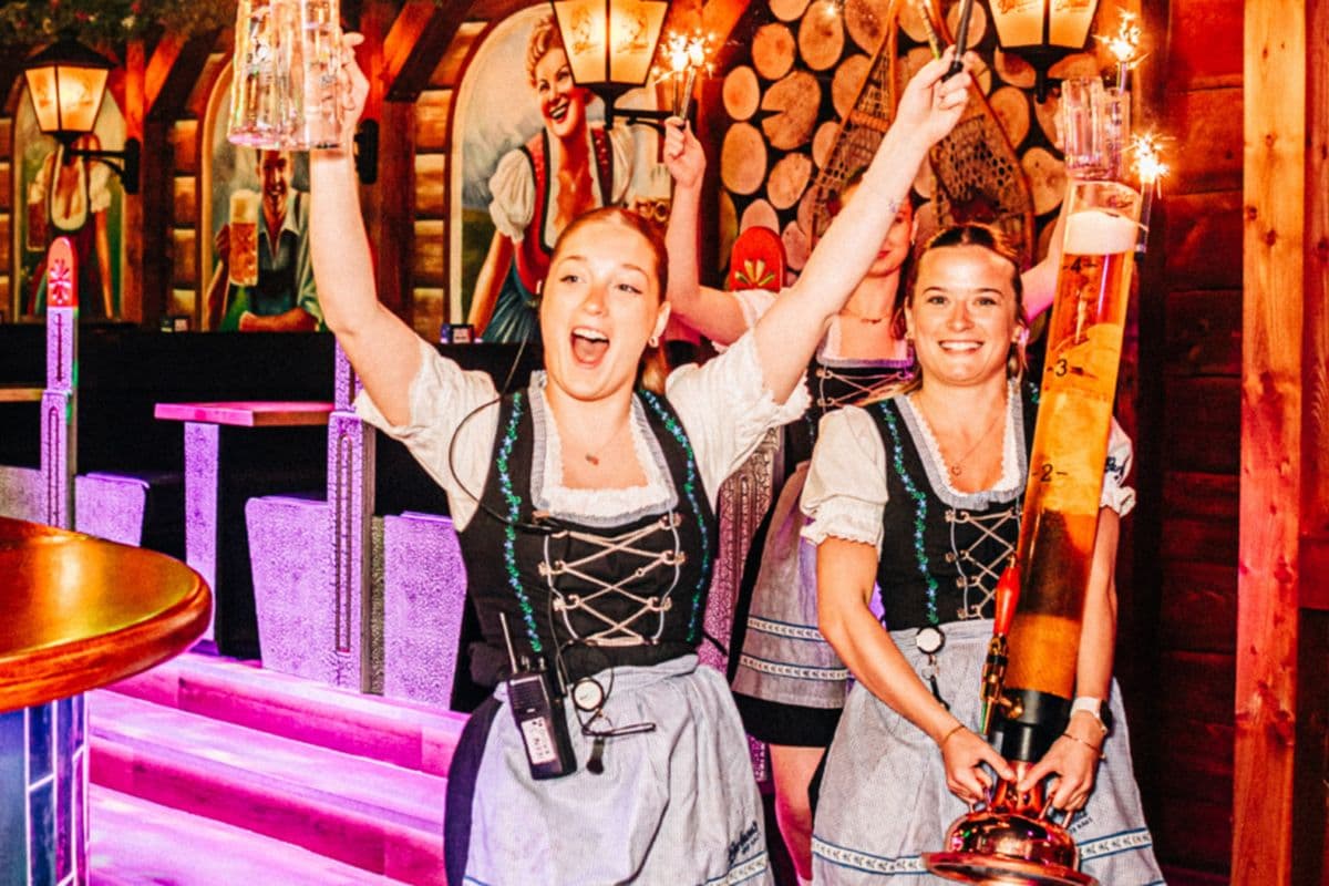 Bartenders in dirndls celebrating behind the bar at a Barbara's Bier Haus