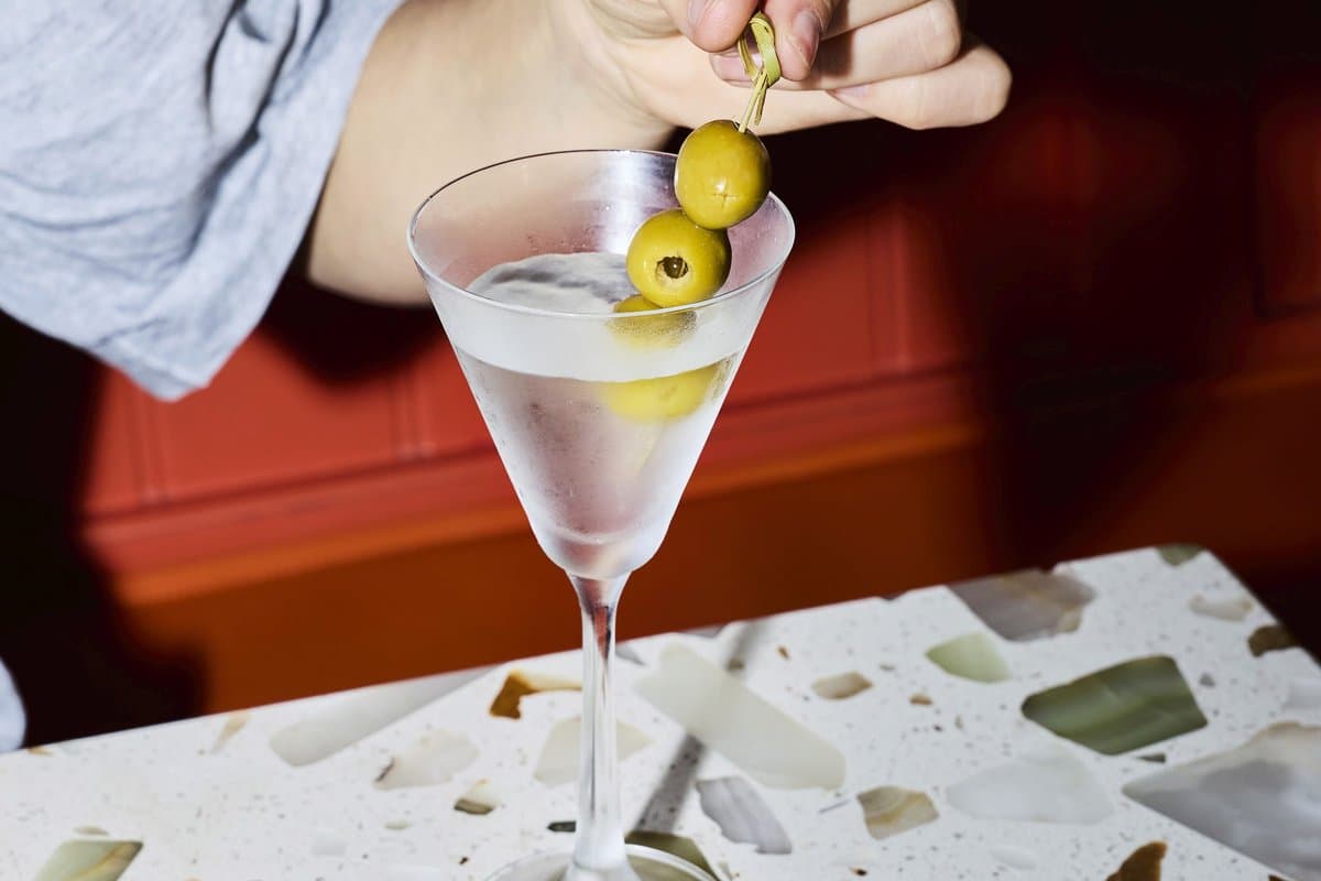 A martini garnished with green olives on a terrazzo table at Spring St. Pizza's bar