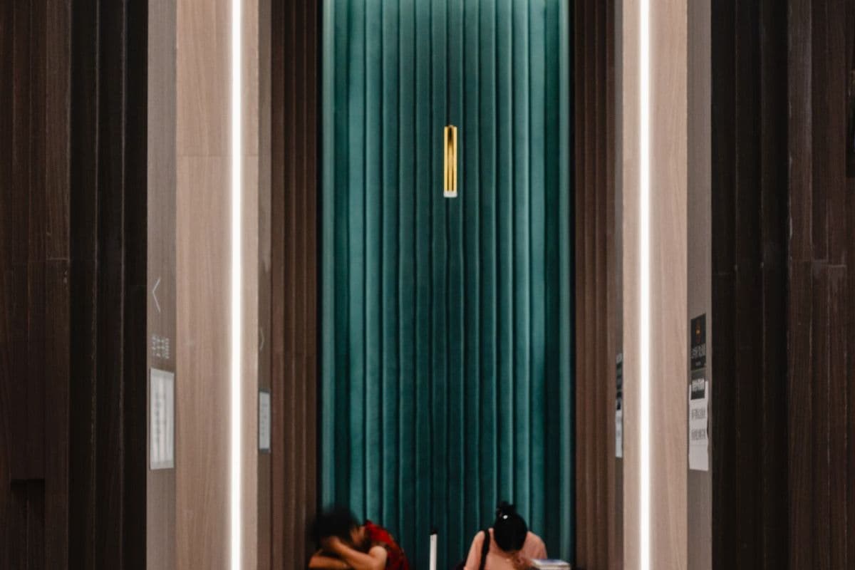 Two guests sitting in a long hotel corridor