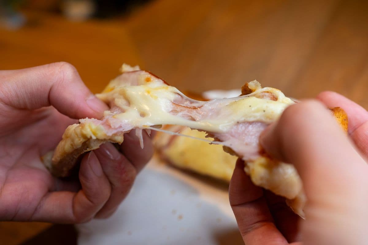 A toasted sandwich being pulled apart with melted cheese stretching between the halves