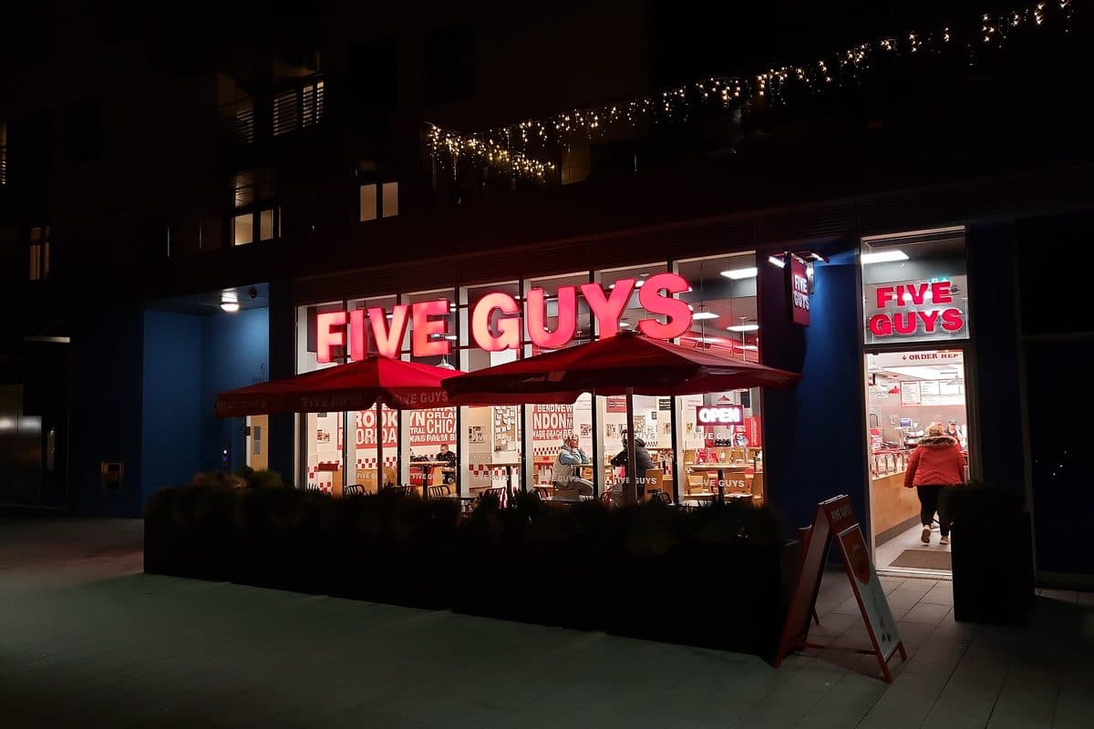 A Five Guys restaurant lit up at night at Brighton Marina