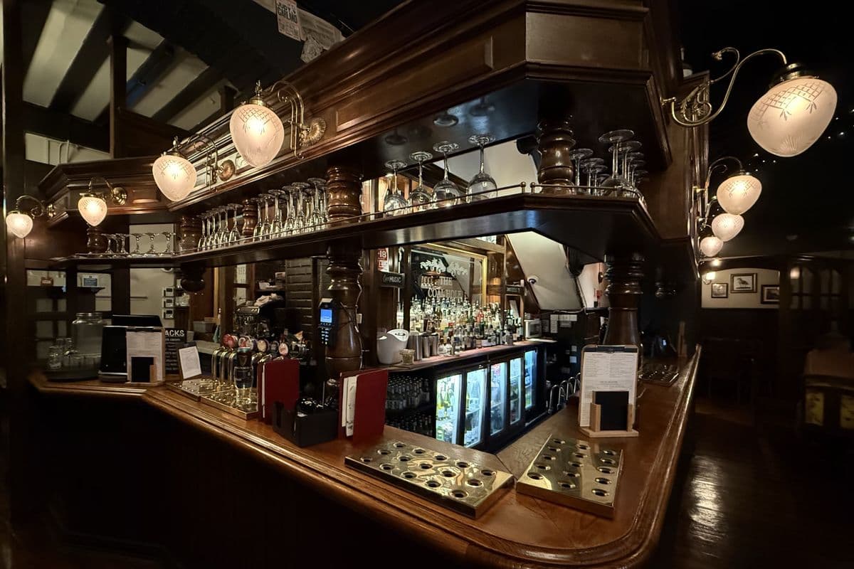 The empty bar counter of a traditional pub with lamps and polished wood