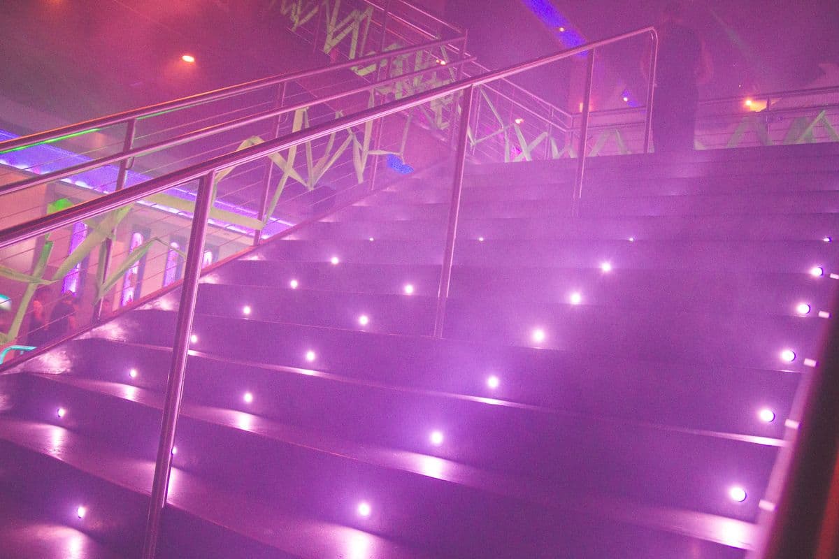 Stairs leading into a busy nightlife venue with warm lighting
