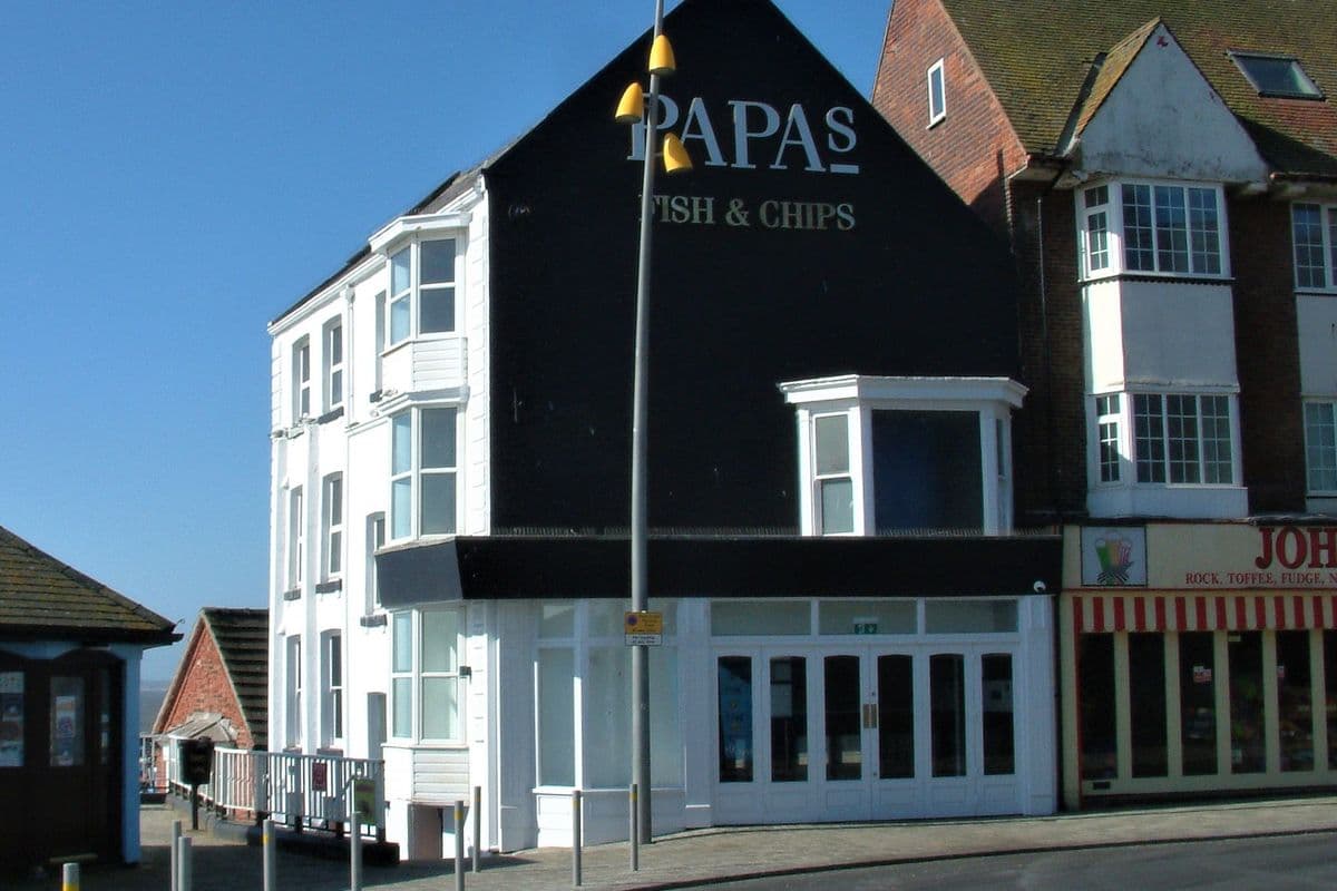 The exterior of a busy fish and chips shop with customers outside
