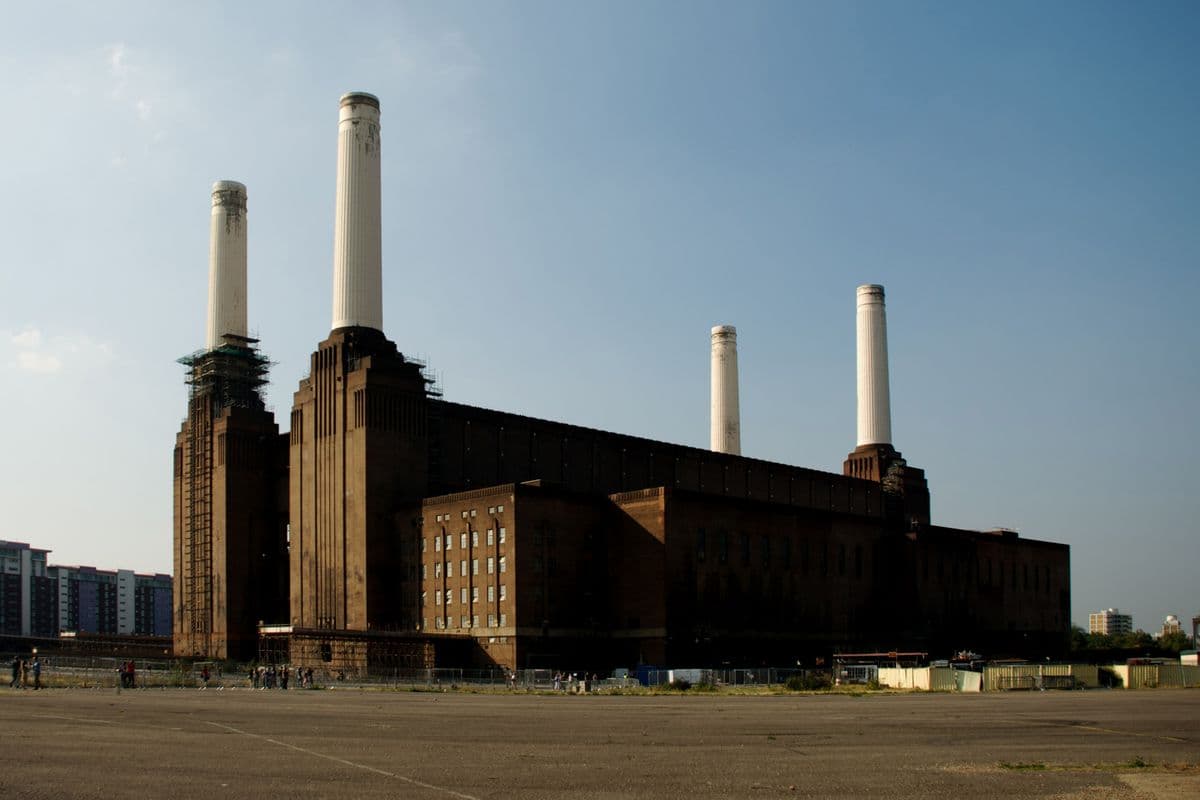 Battersea Power Station seen across the water under a blue sky
