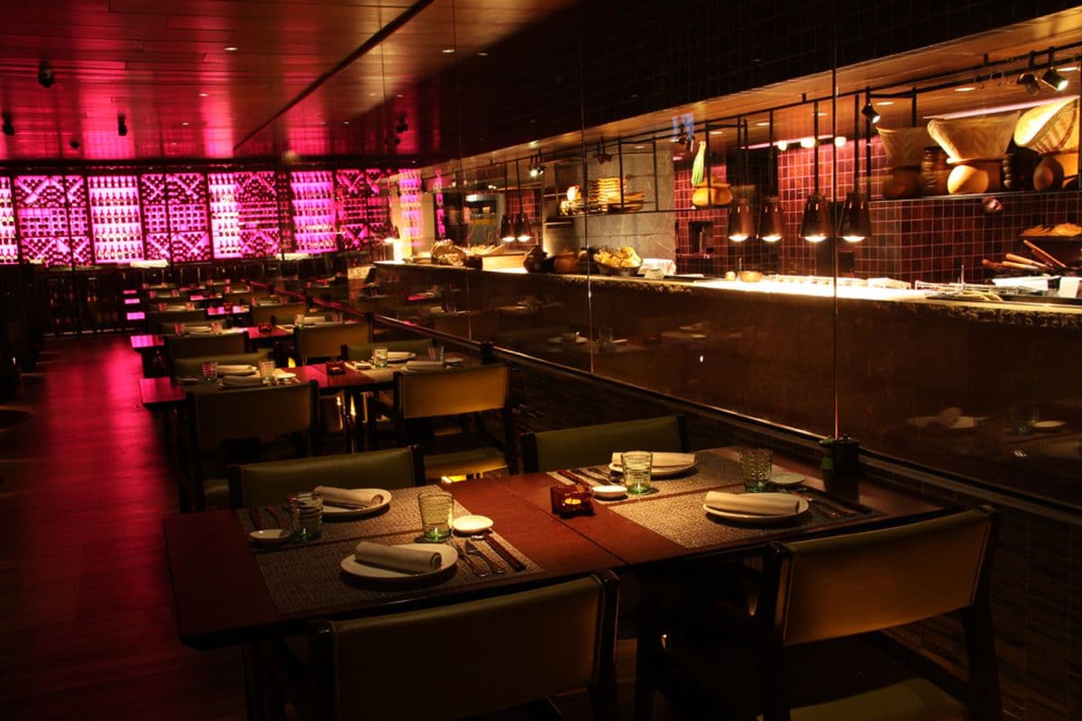 A warmly lit pan-Asian restaurant dining room with set tables