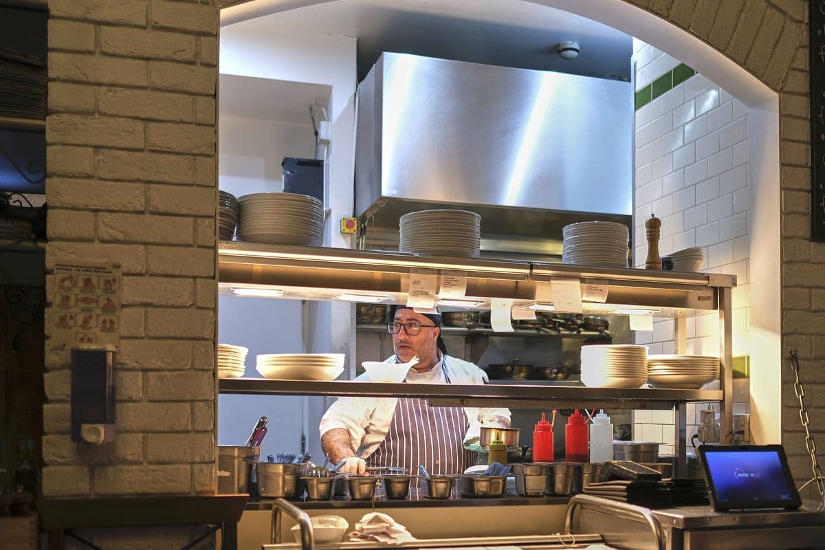 A chef working at the pass in an open restaurant kitchen
