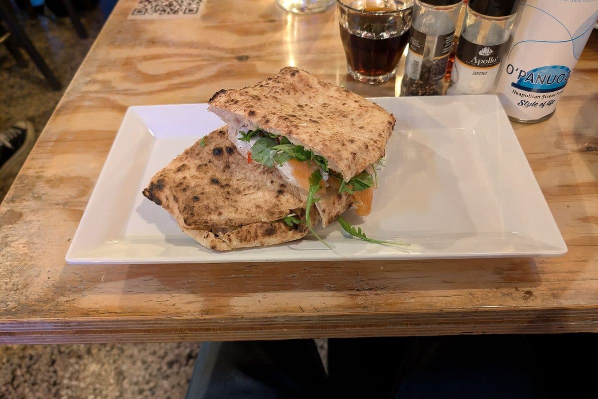 A panuozzo sandwich filled with greens on a white plate