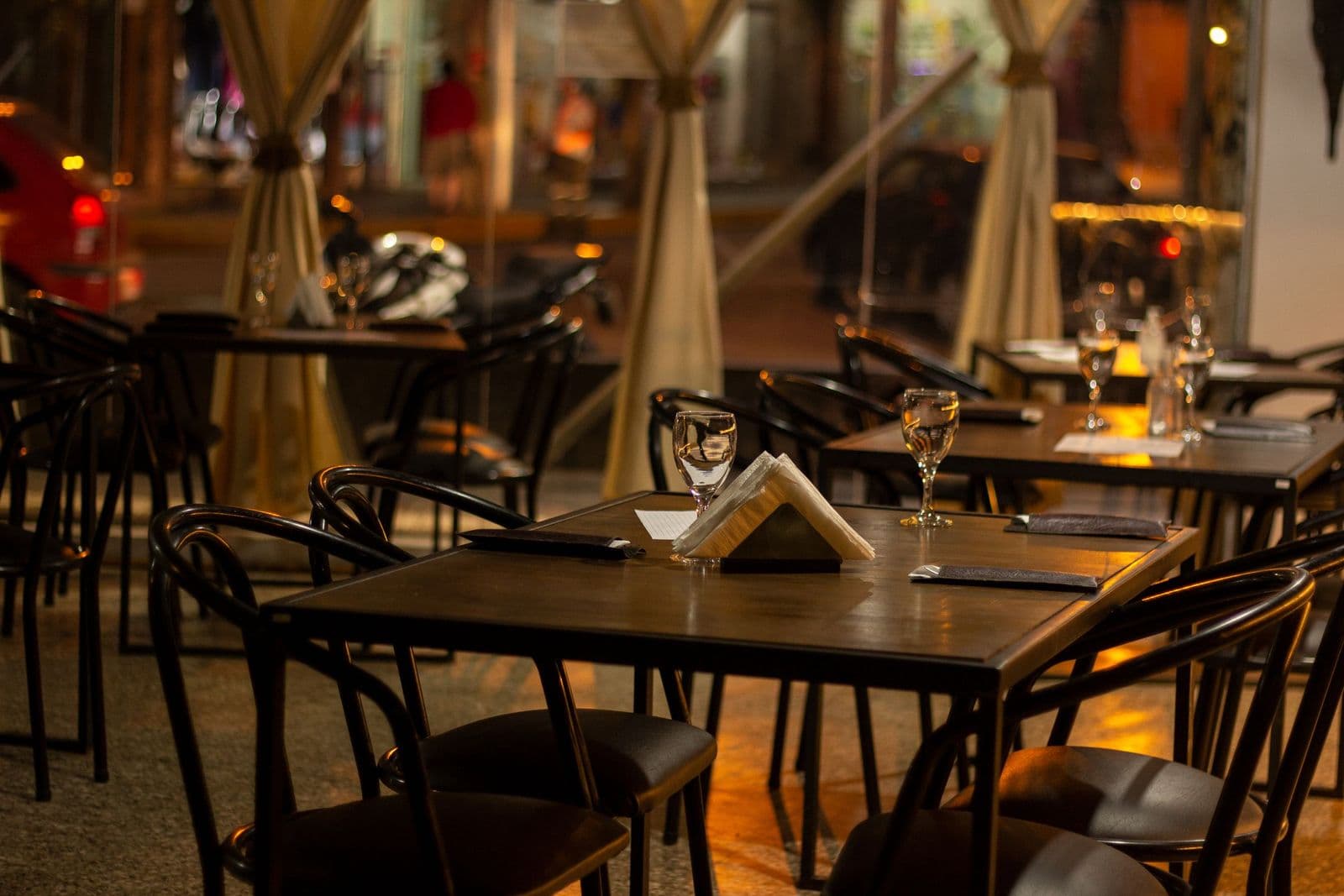 Warmly lit, empty restaurant with tables set for service