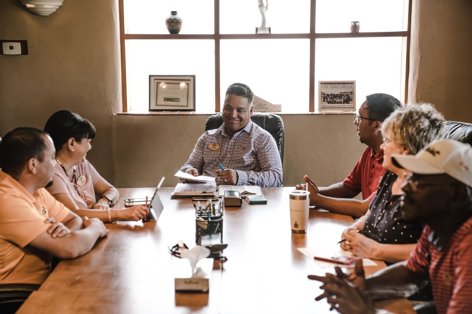 A small team meeting around a wooden table with laptops and notebooks