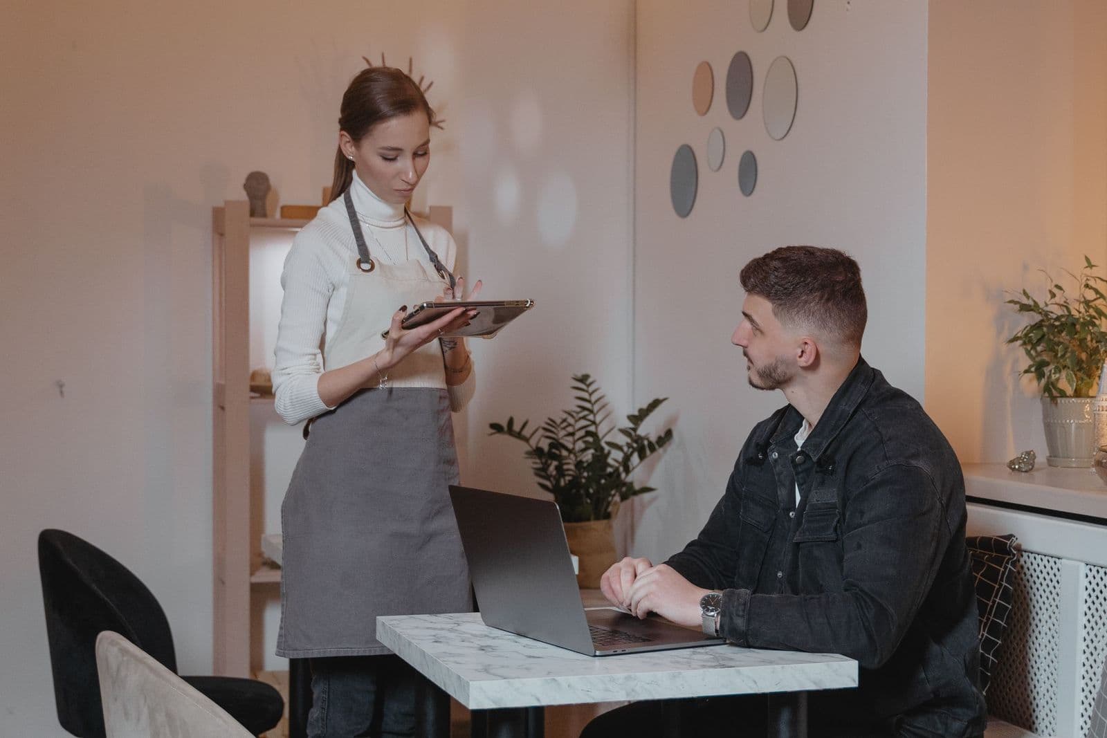 Server talking with a seated guest in a cafe