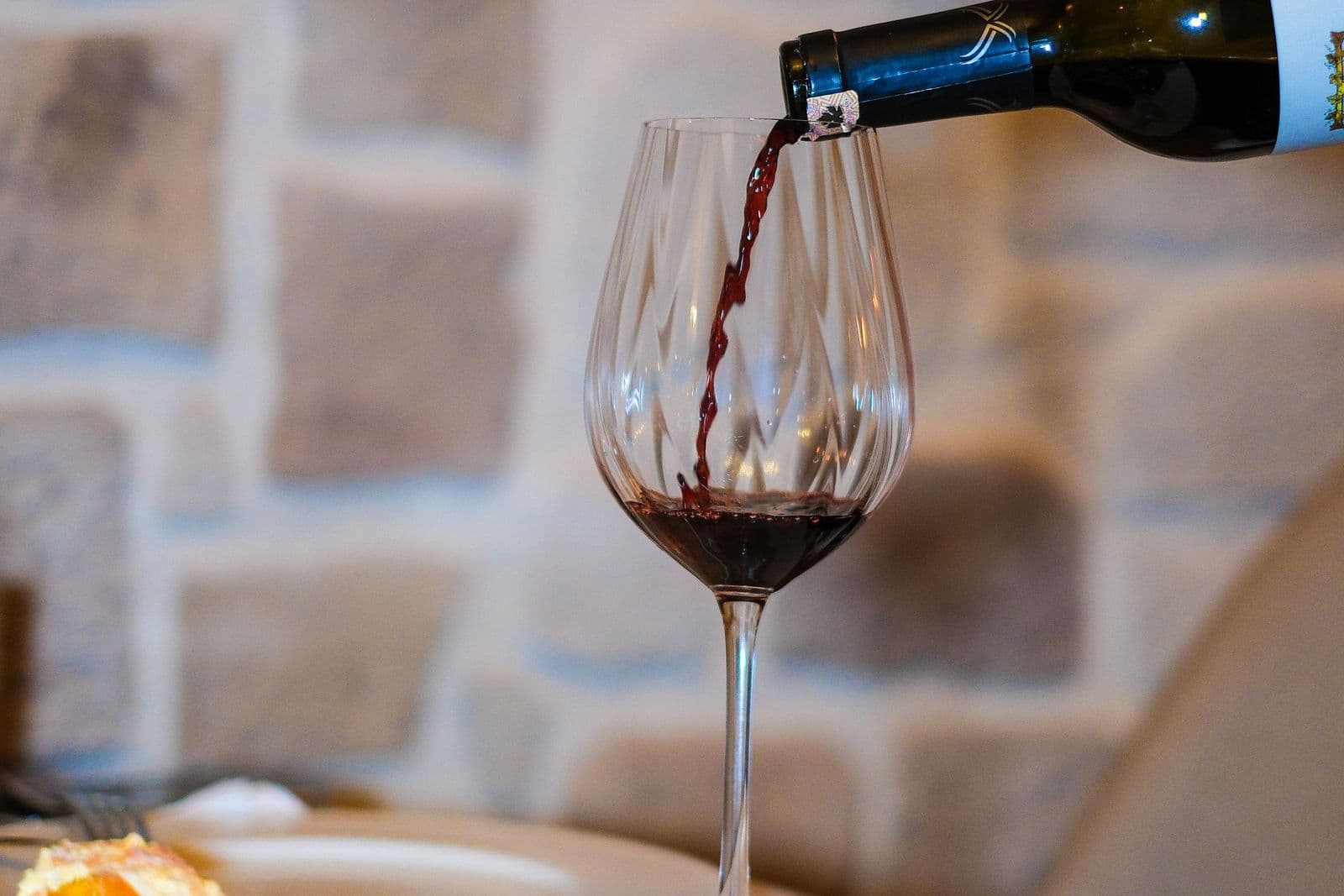 Red wine being poured into a glass at the table