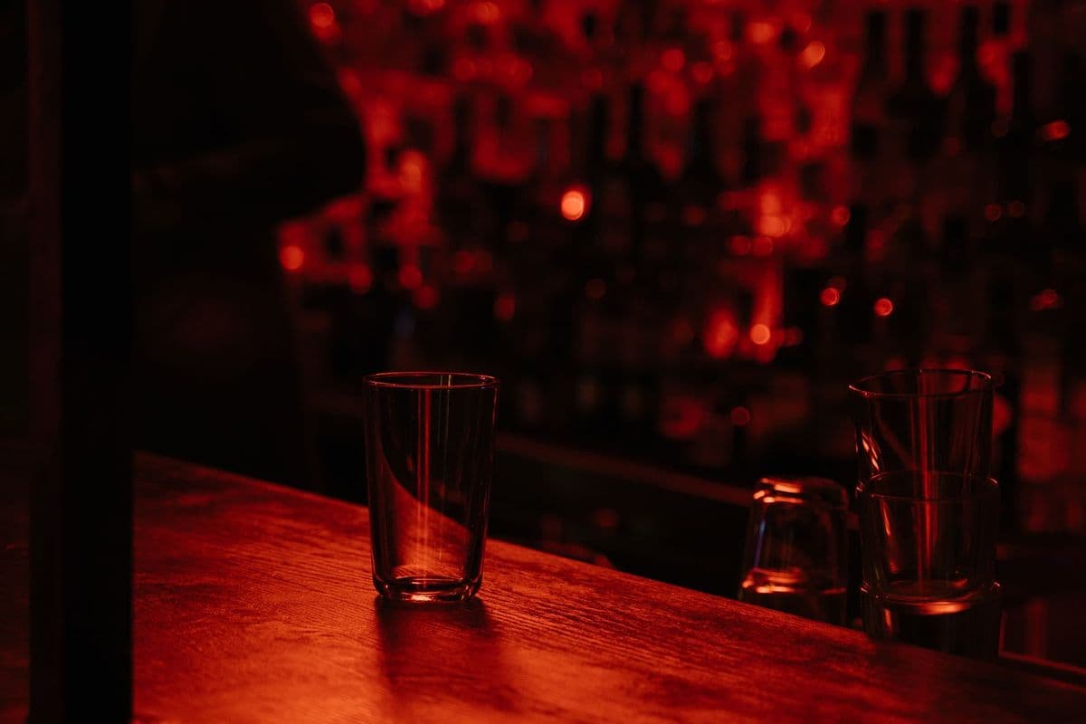 A glass on a bar counter in a dim room lit in deep red