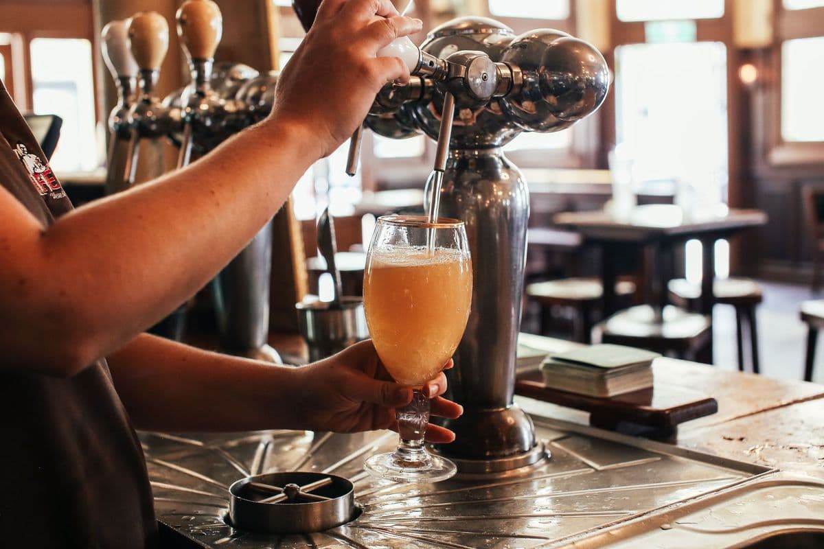 A bartender pouring a pint of beer from a tap