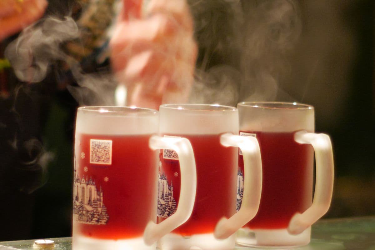 Three steaming glass mugs of mulled wine on a bar