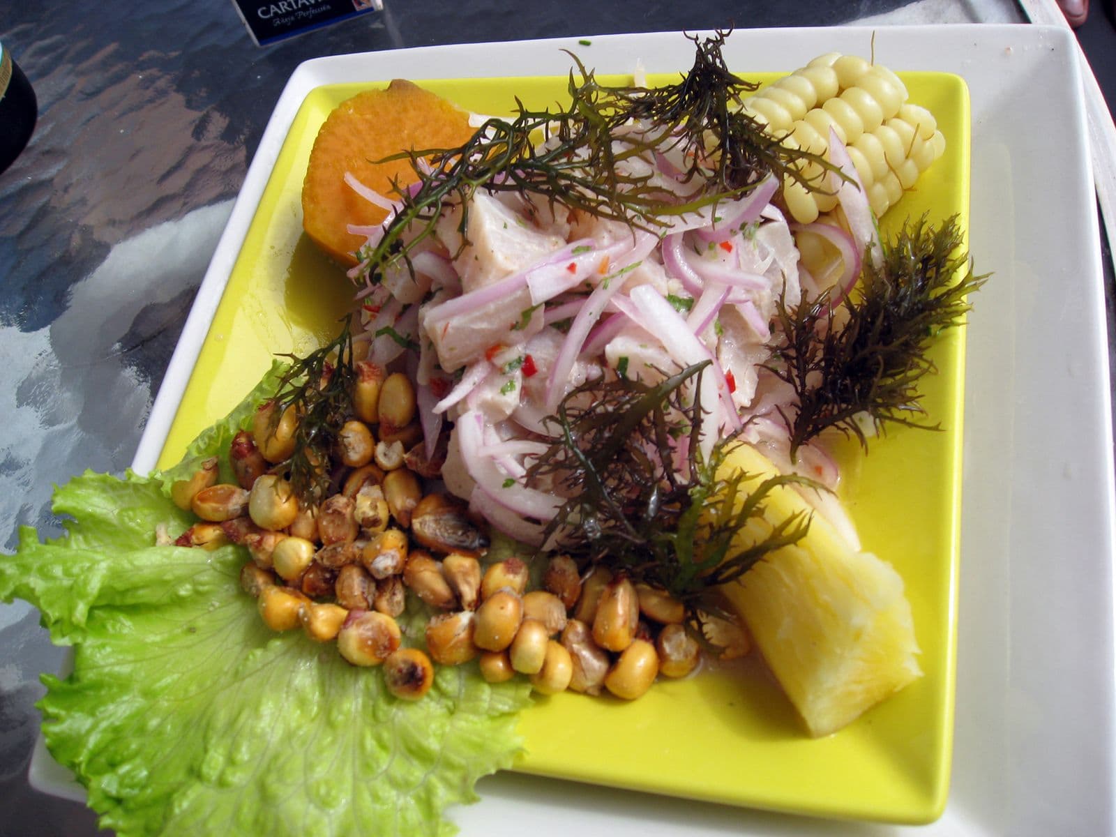 A plate of Peruvian ceviche with red onion, corn and sweet potato