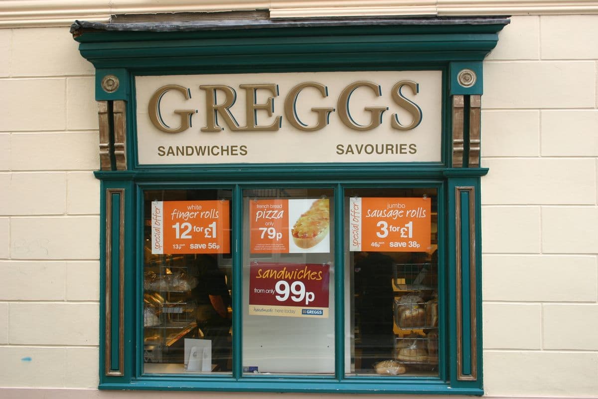 A small Greggs shop front with sandwich and savoury deals in the window