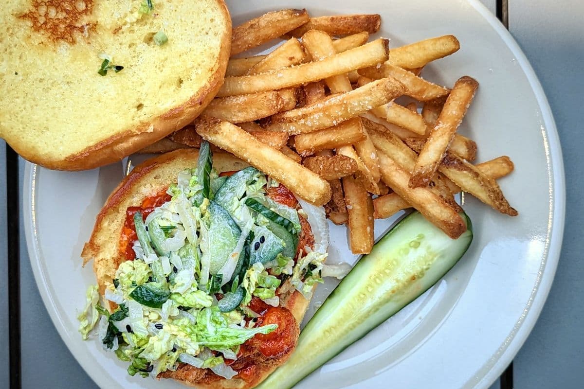 A fried chicken sandwich with slaw and a side of chips