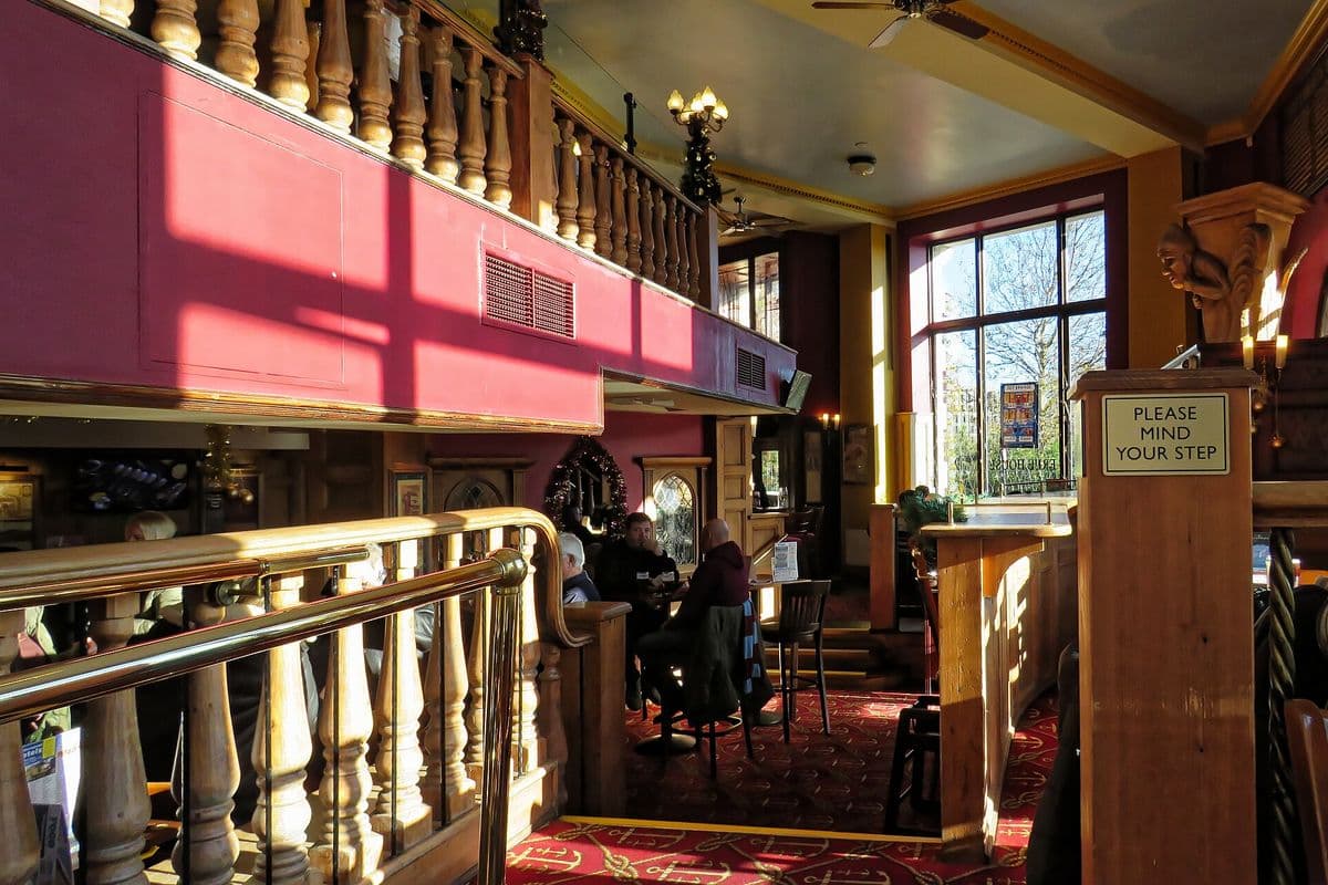 The interior of a busy Wetherspoon pub with wooden seating and hanging lights