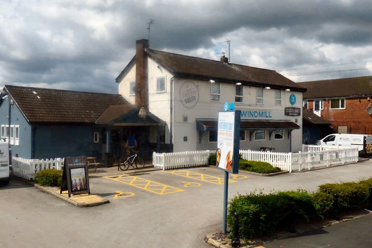 The Windmill pub in Denton, a white two-storey building with a car park in front
