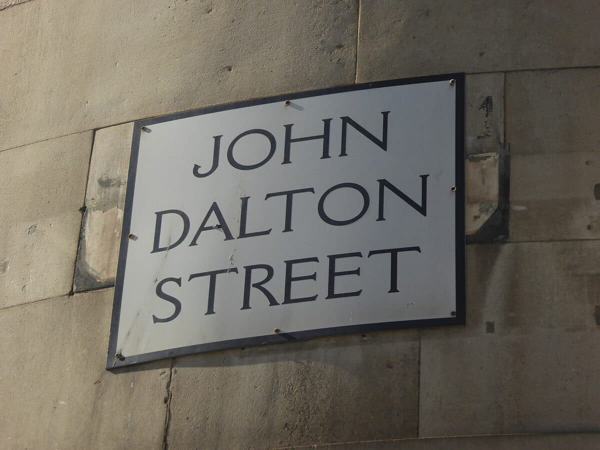 The John Dalton Street sign on a stone wall in Manchester city centre