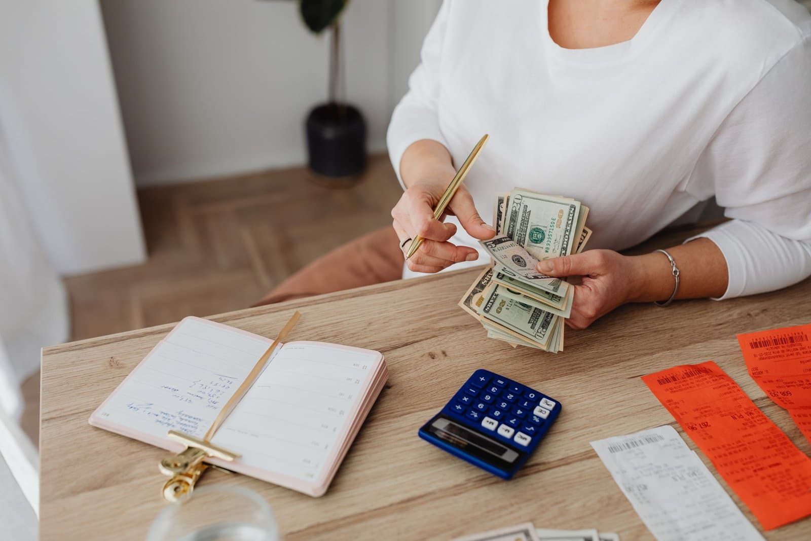Person at a desk sorting receipts and cash with a calculator