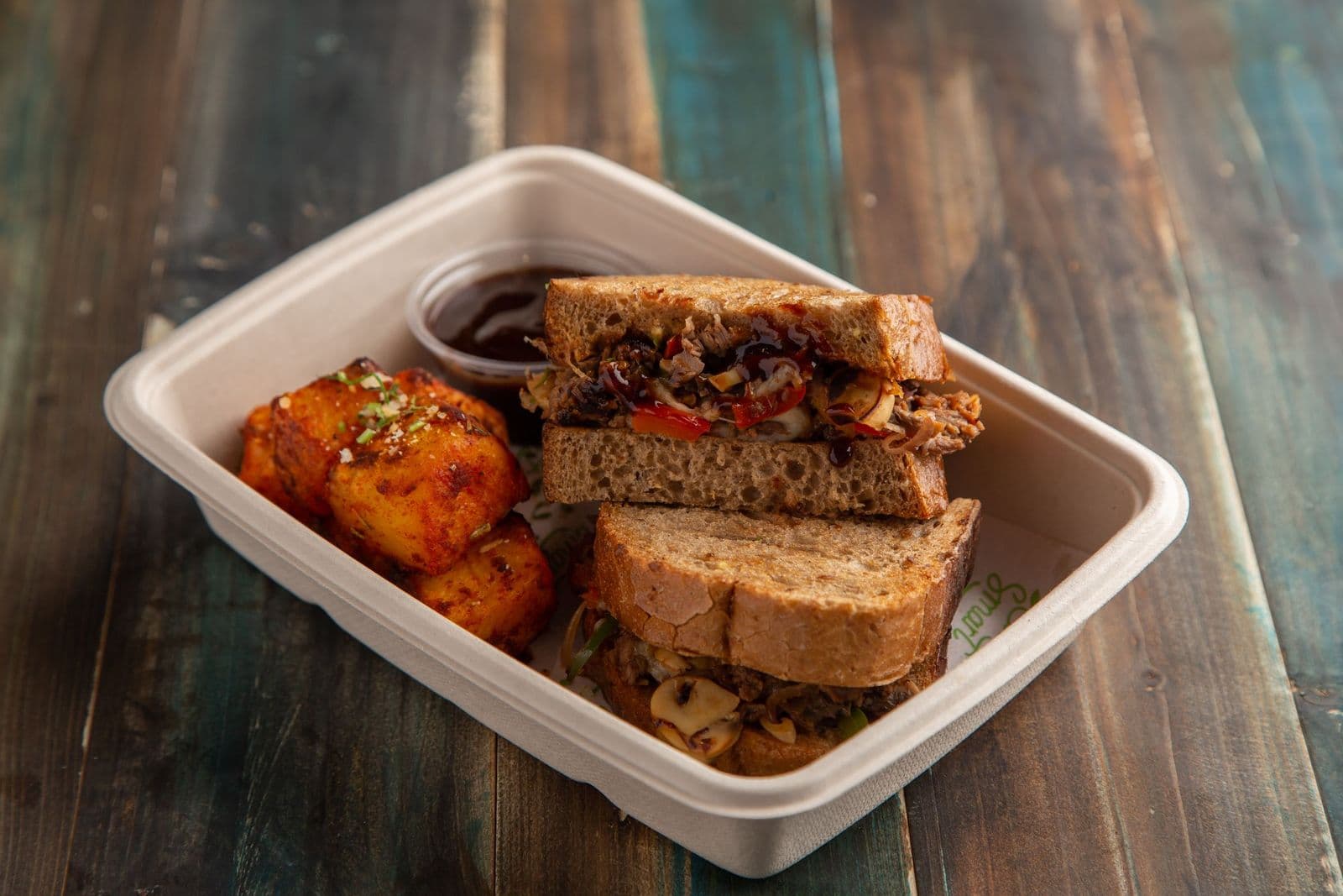 Sandwich and potatoes in a takeaway box