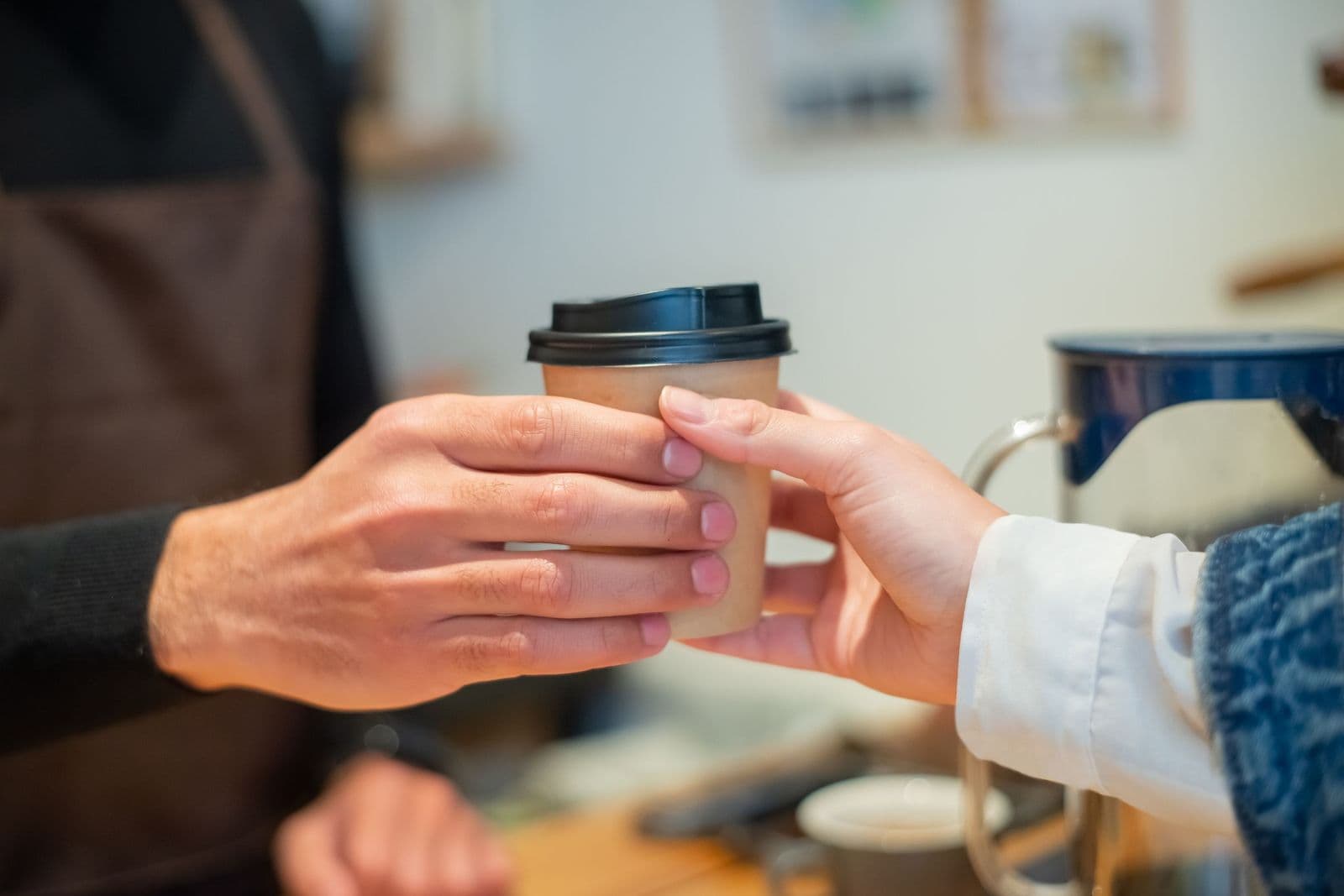 Barista handing a takeaway coffee to a customer