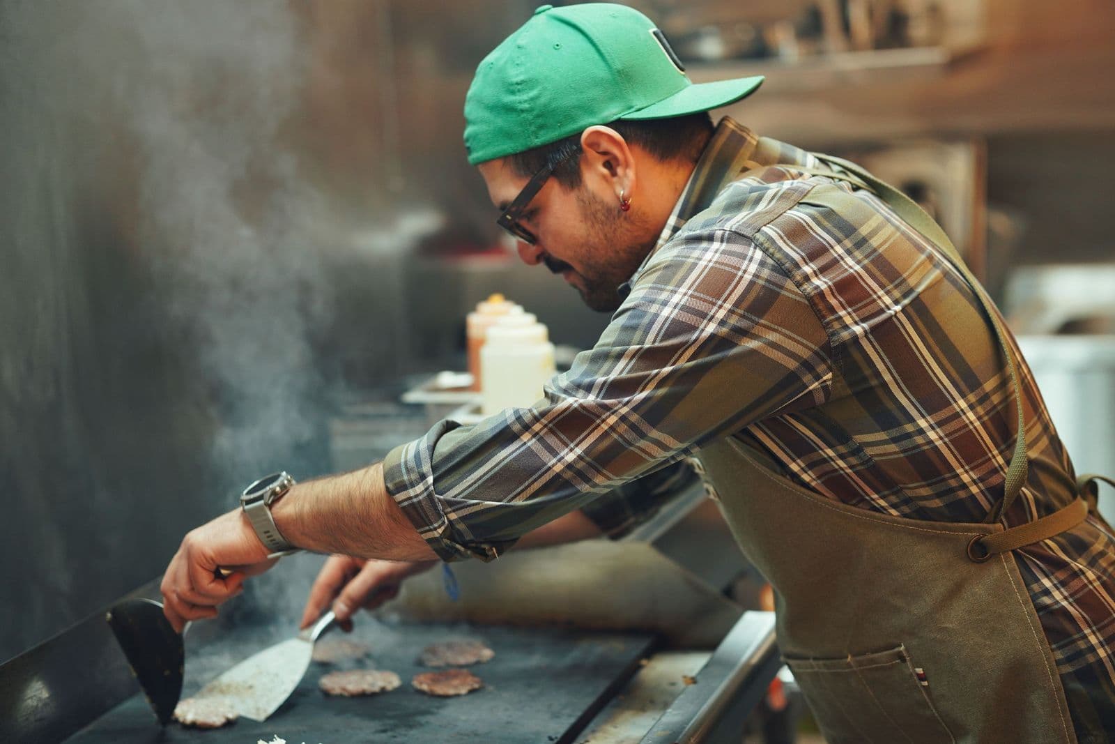 Chef cooking burgers on a flat-top grill