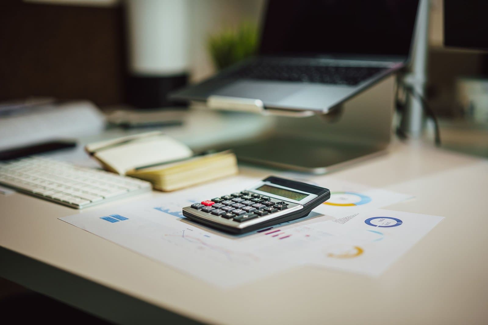 A laptop, calculator and documents on a desk