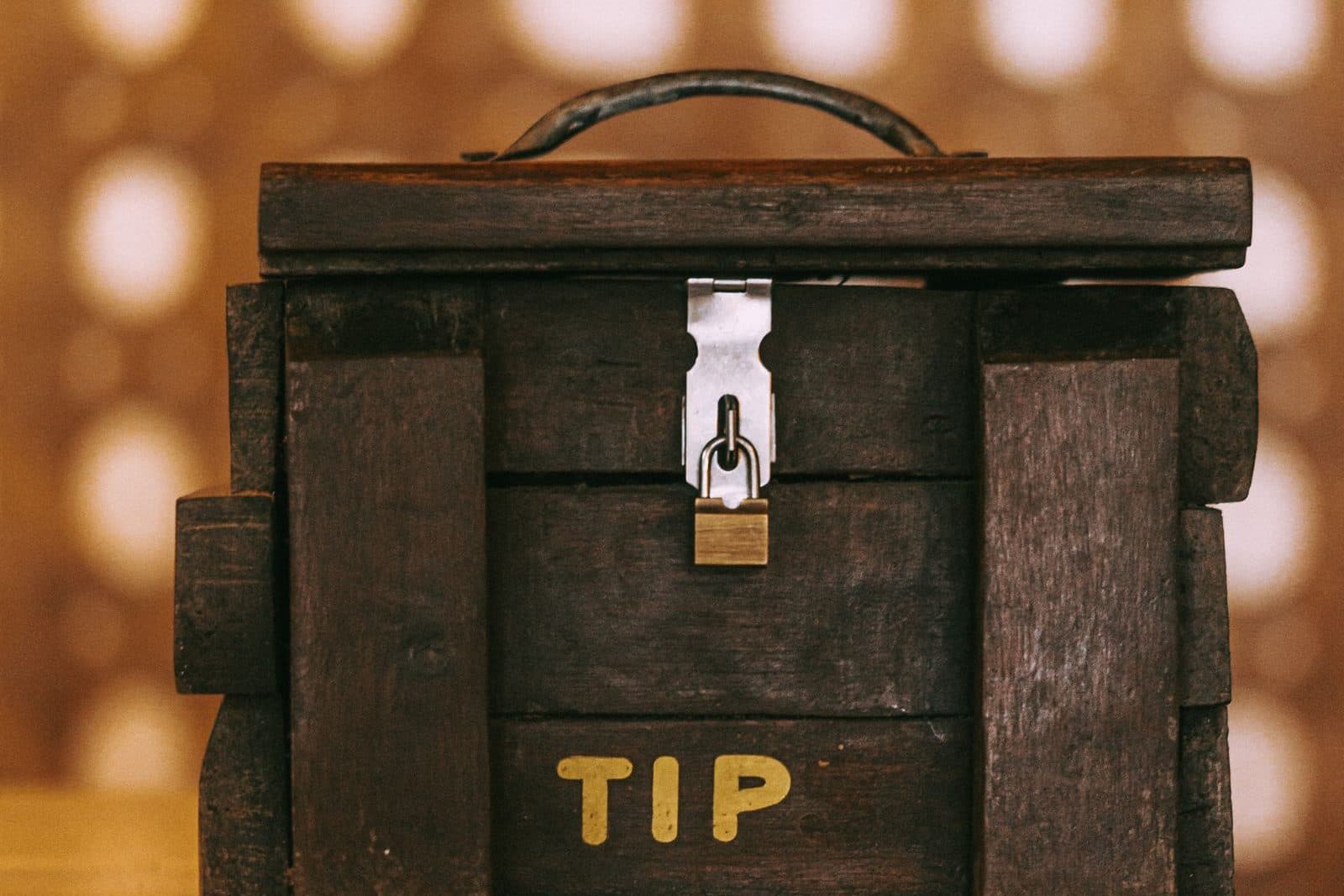 A wooden tip box with a small padlock on a bar