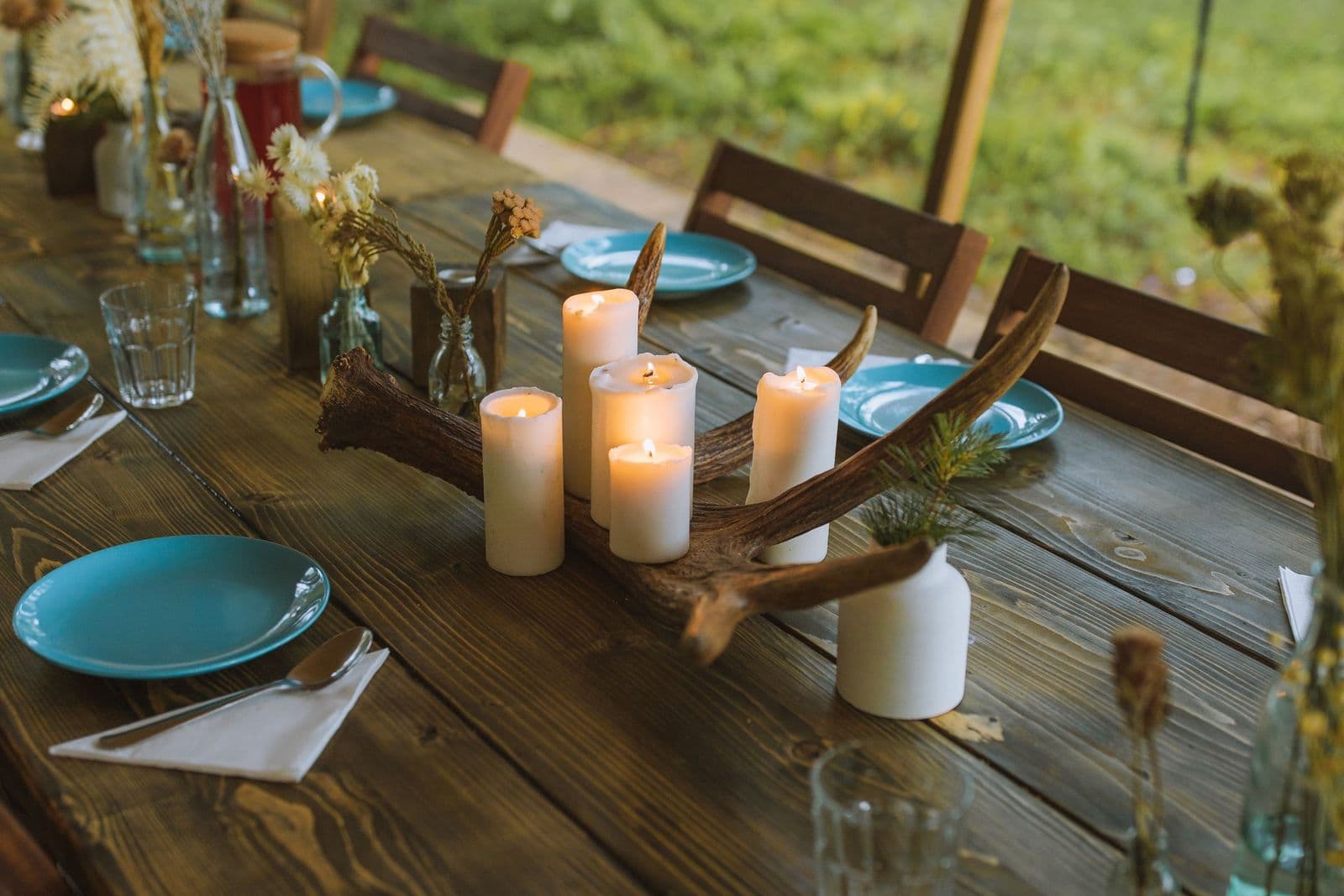 Candles on a long rustic table set for a group dinner