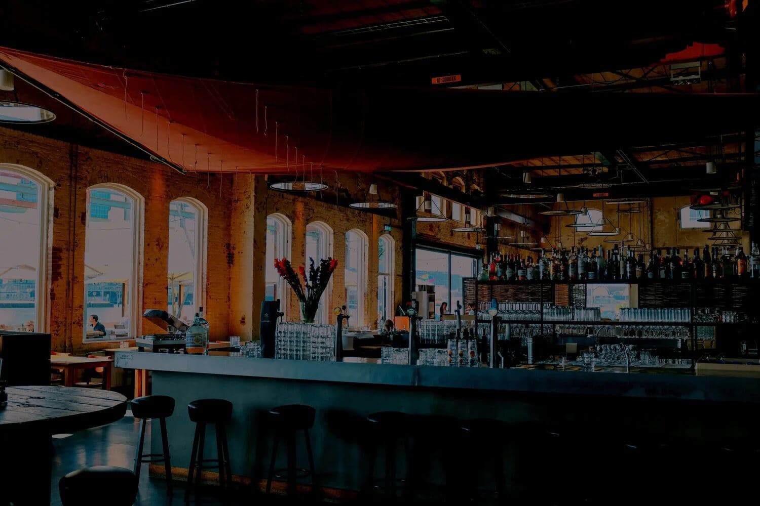 Large bar and restaurant interior with arched windows and exposed brick