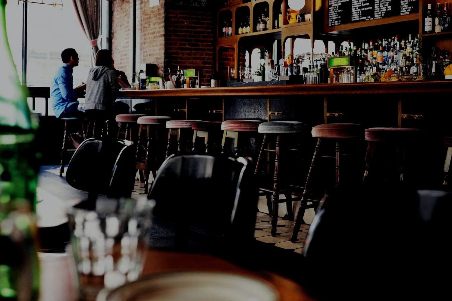 Drinkers sitting at a busy bar counter lined with stools